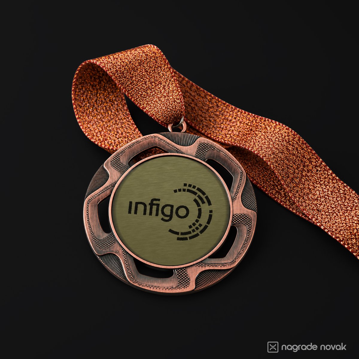 Bronze medal with the black Infigo logo on a gold insert, lying on a dark surface with a copper glitter ribbon draped over it