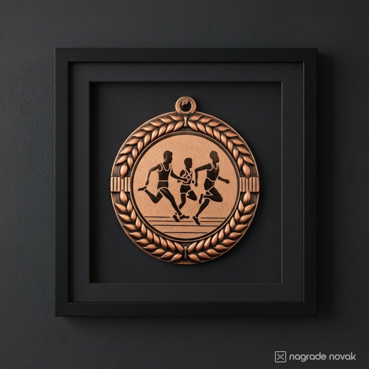 Bronze medal with a laurel wreath and three runners mounted inside a black square frame on a dark grey wall