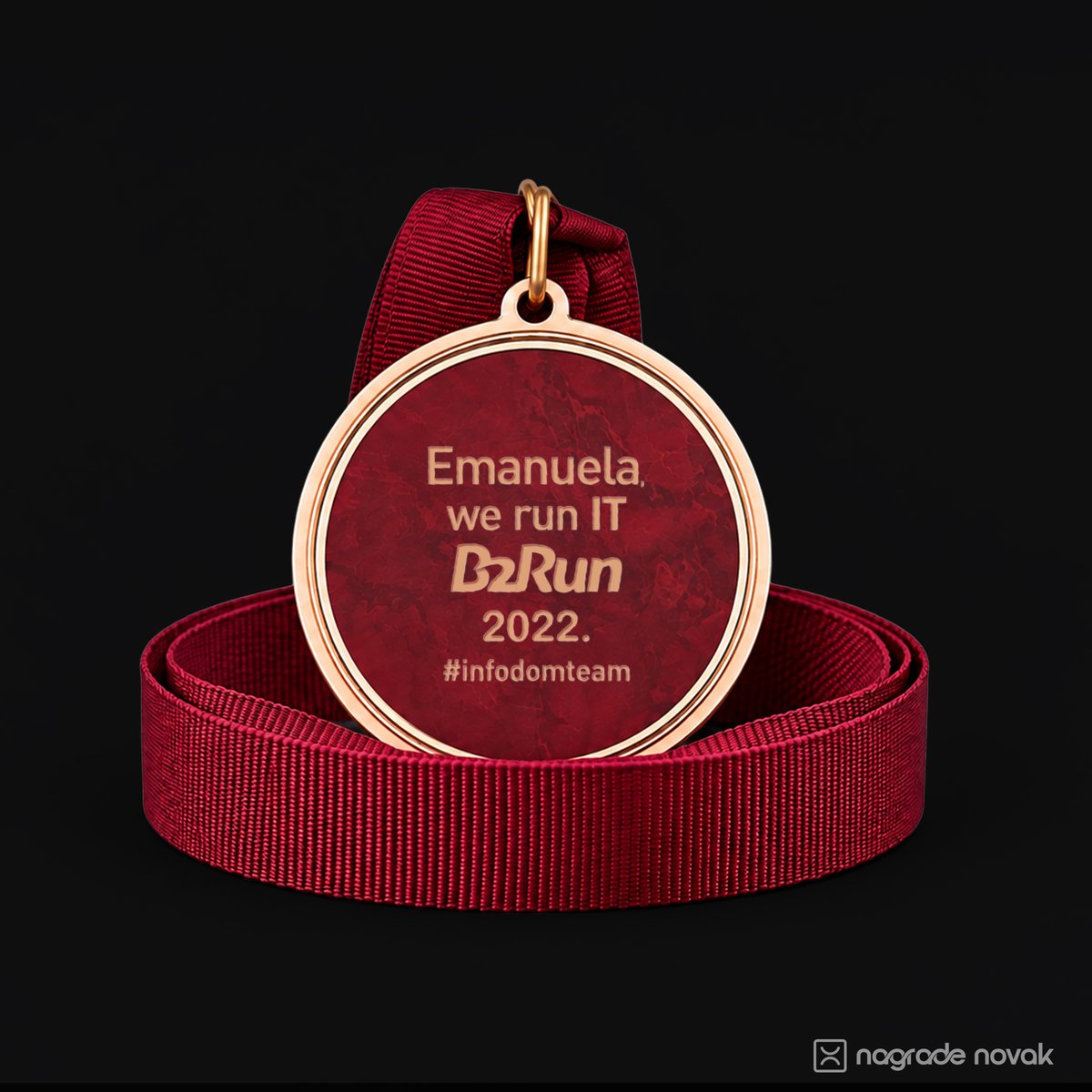 Maroon and gold medal back insert reading “Emanuela, we run IT B2Run 2022”, resting on a coiled maroon ribbon on a black background