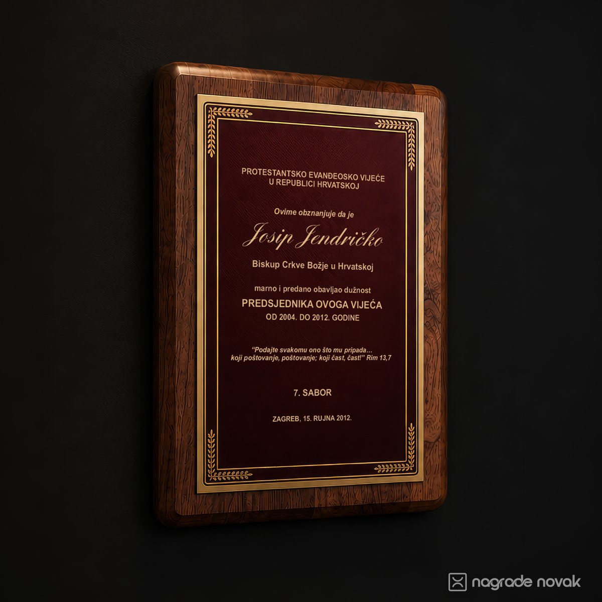 Rectangular walnut wooden plaque with a burgundy plate and gold ornamental border, engraved with an official acknowledgement text and signature-style name, on a dark wall