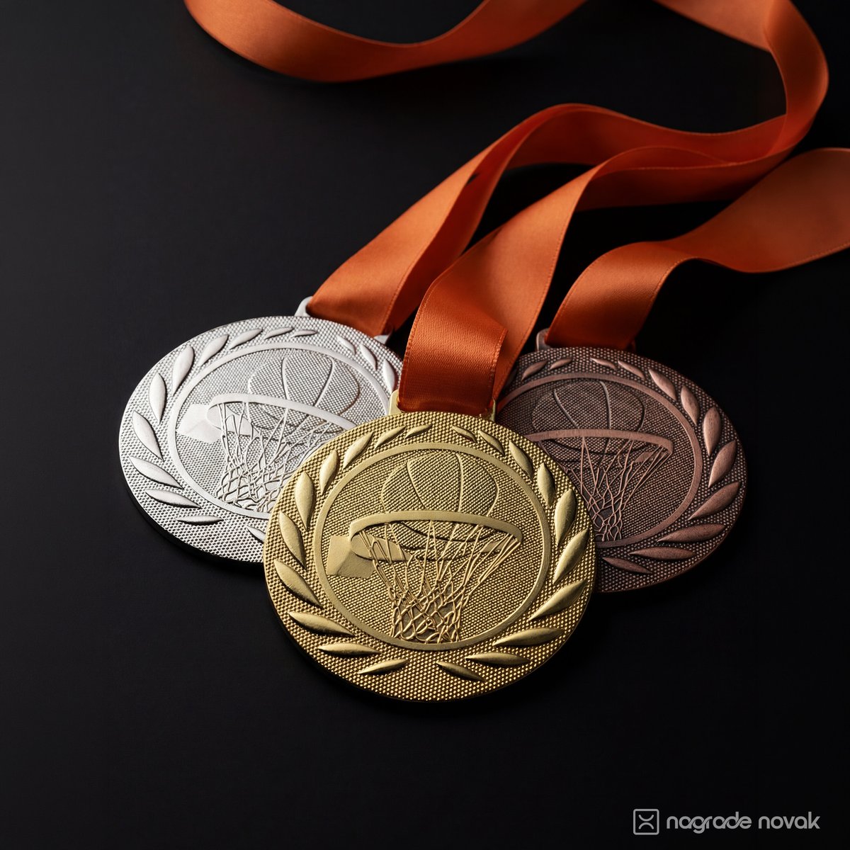 Silver, gold and bronze basketball medals with embossed hoop and laurel, on orange ribbons