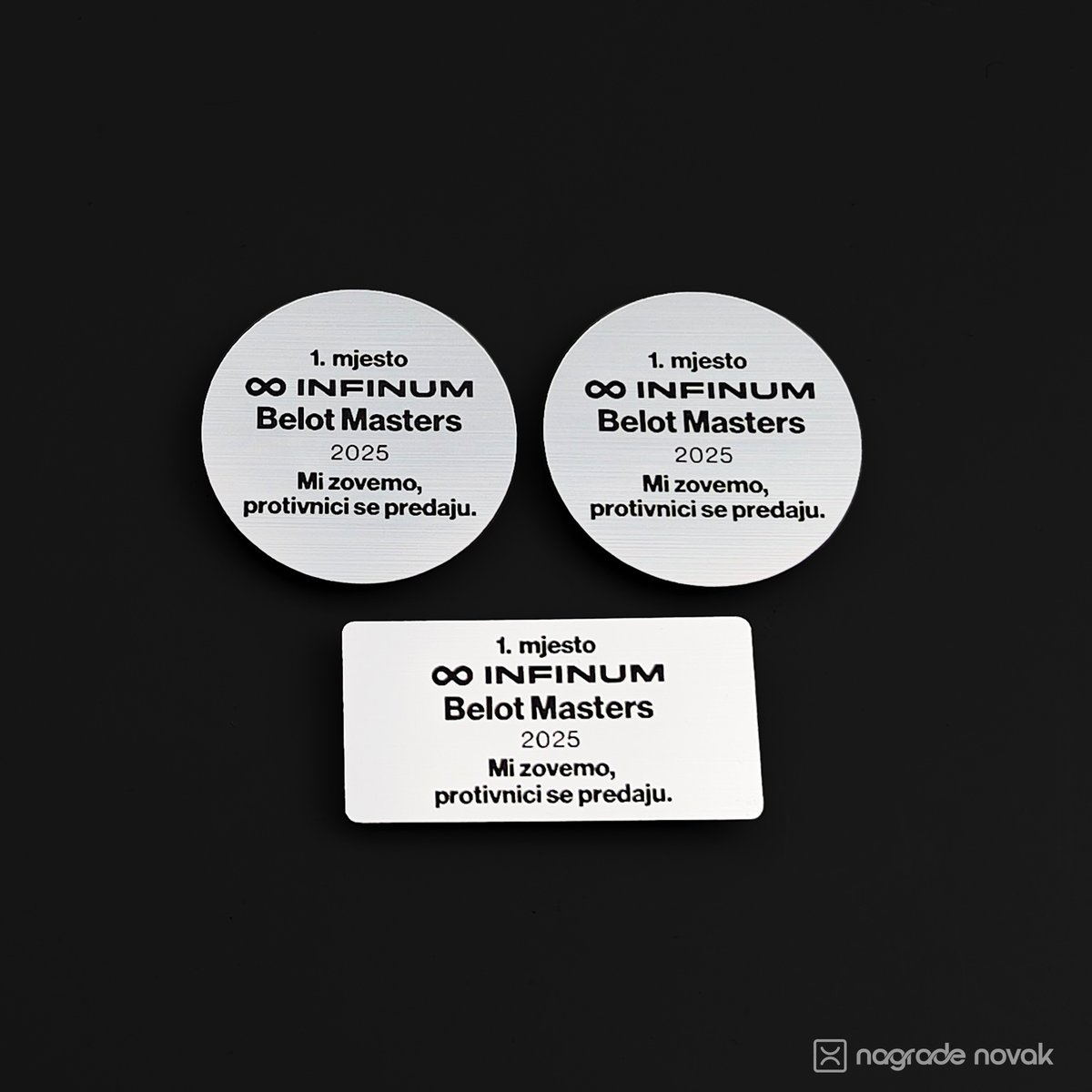 Two round and one rectangular silver plates with engraved text, arranged on a dark background.