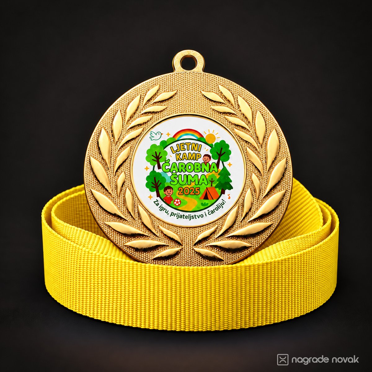 Gold medal with a laurel wreath and the colourful camp insert on a coiled yellow ribbon, on a dark background