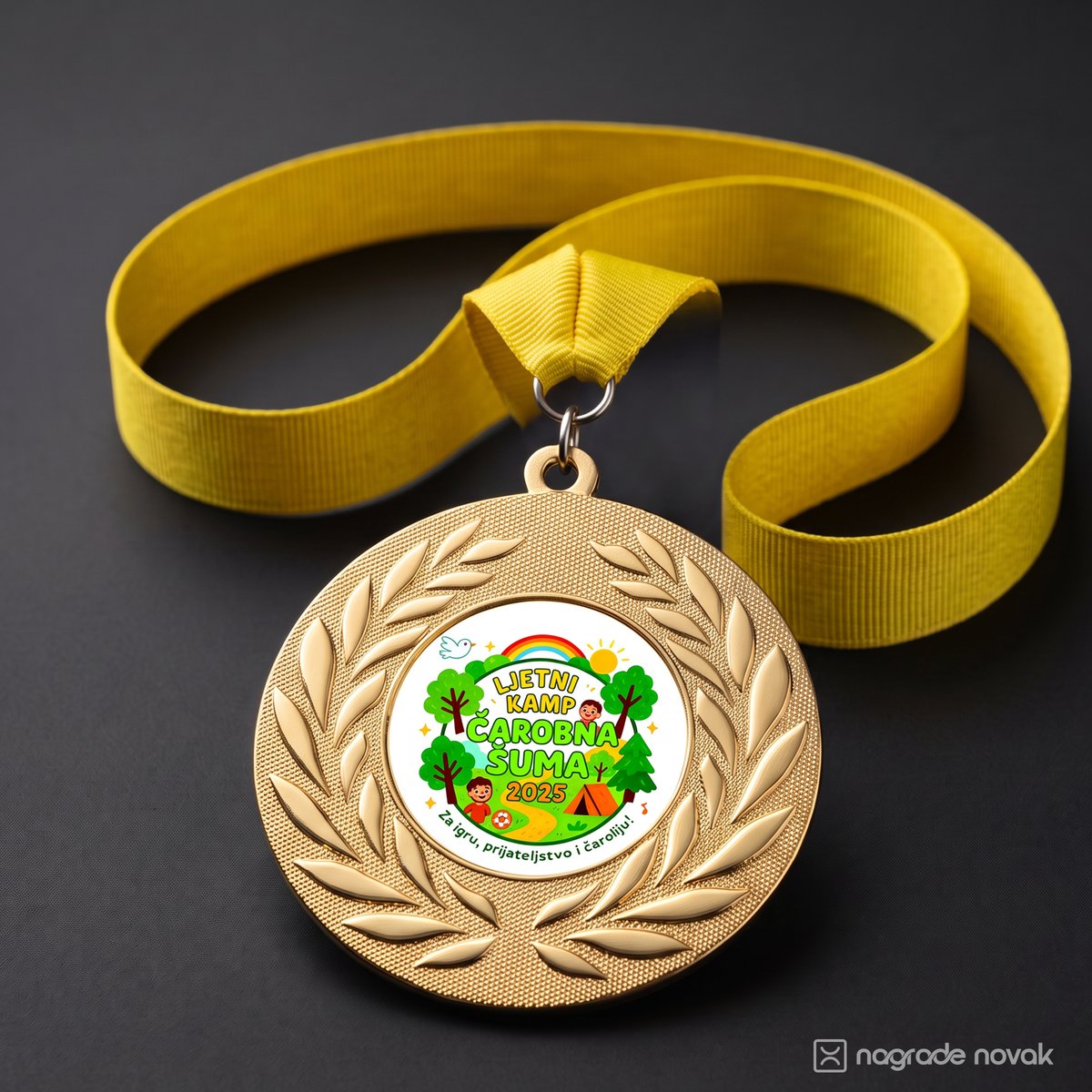 Gold medal with a laurel wreath and the camp insert on a yellow ribbon, lying on a dark grey surface
