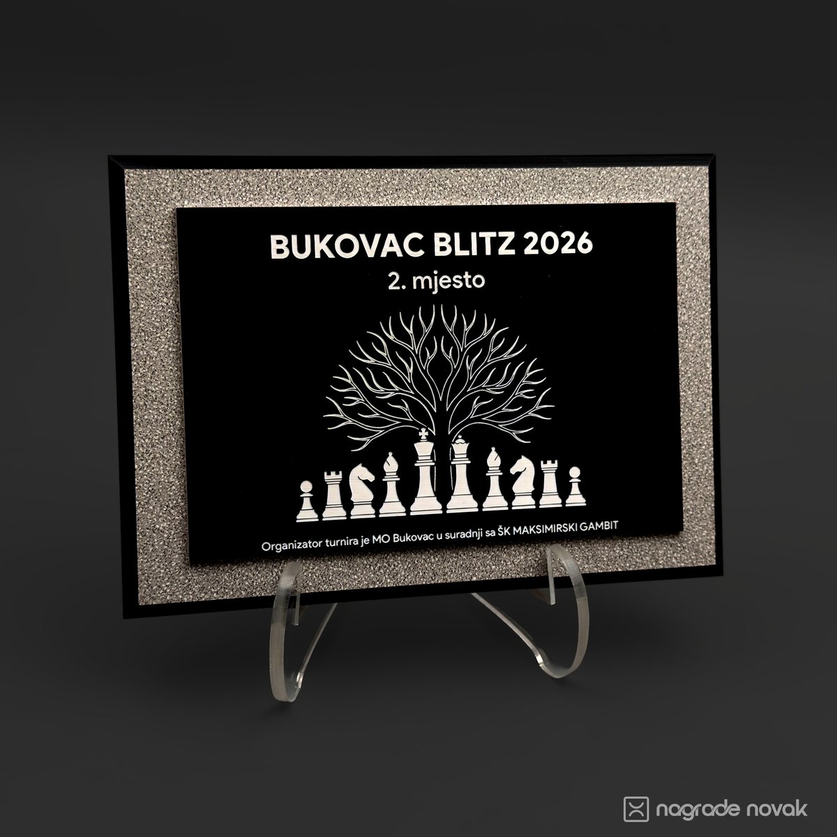 Award plaque engraved "BUKOVAC BLITZ 2026, 2. mjesto" with a tree above chess pieces, standing on a clear acrylic stand against a dark background