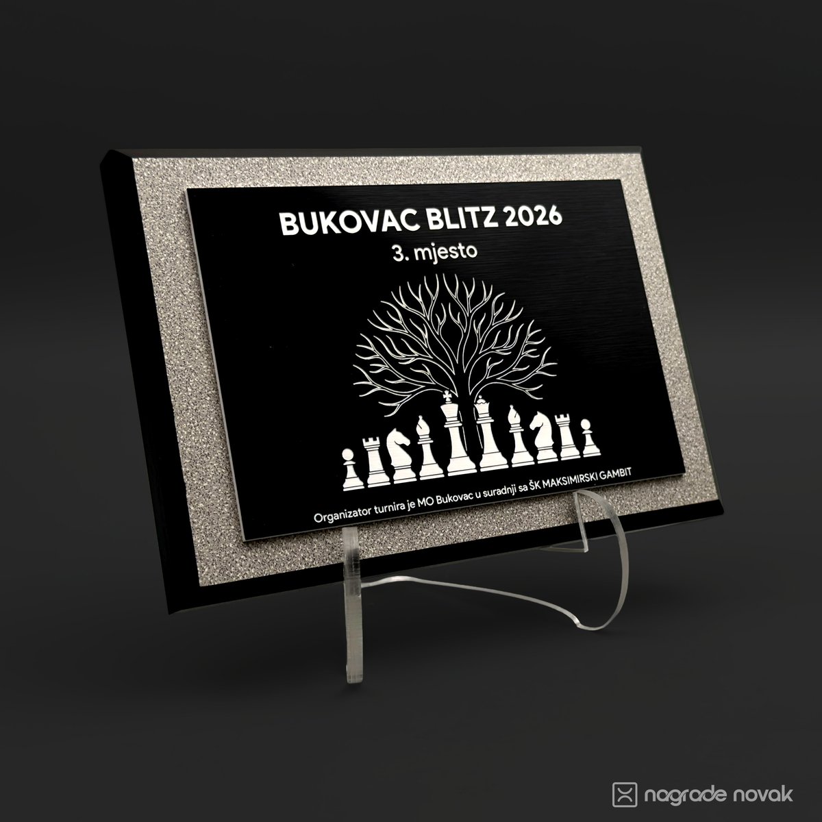Award plaque engraved "BUKOVAC BLITZ 2026, 3. mjesto" with a tree above chess pieces, standing on a clear acrylic stand against a dark background