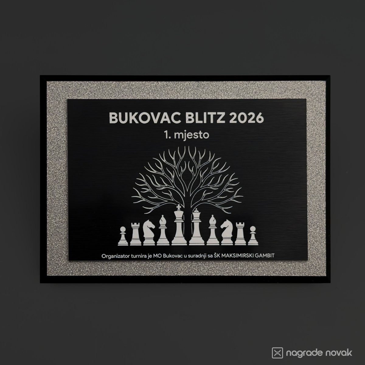 Front view of the 1st place plaque engraved "BUKOVAC BLITZ 2026, 1. mjesto" with a tree above chess pieces, on a dark background