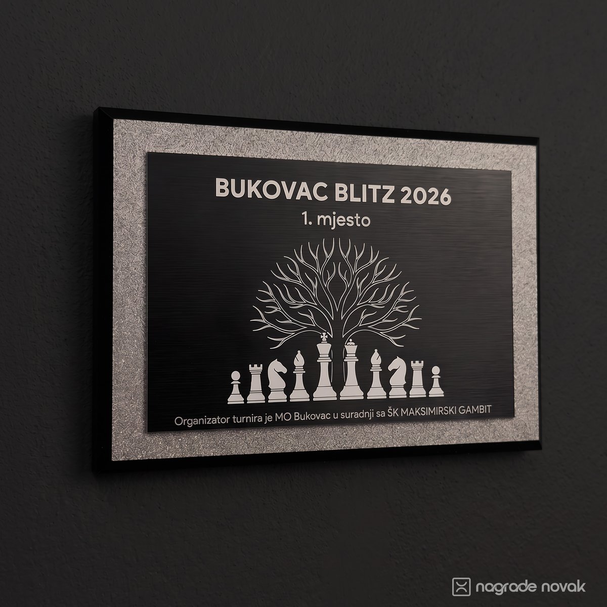 1st place plaque "BUKOVAC BLITZ 2026, 1. mjesto" with a tree above chess pieces, mounted on a dark wall
