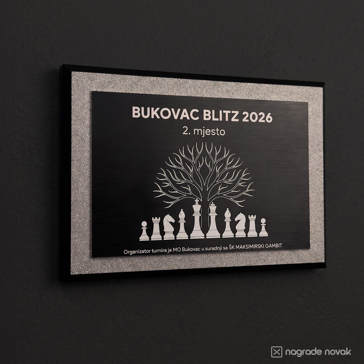 2nd place plaque "BUKOVAC BLITZ 2026, 2. mjesto" with a tree above chess pieces, mounted on a dark wall