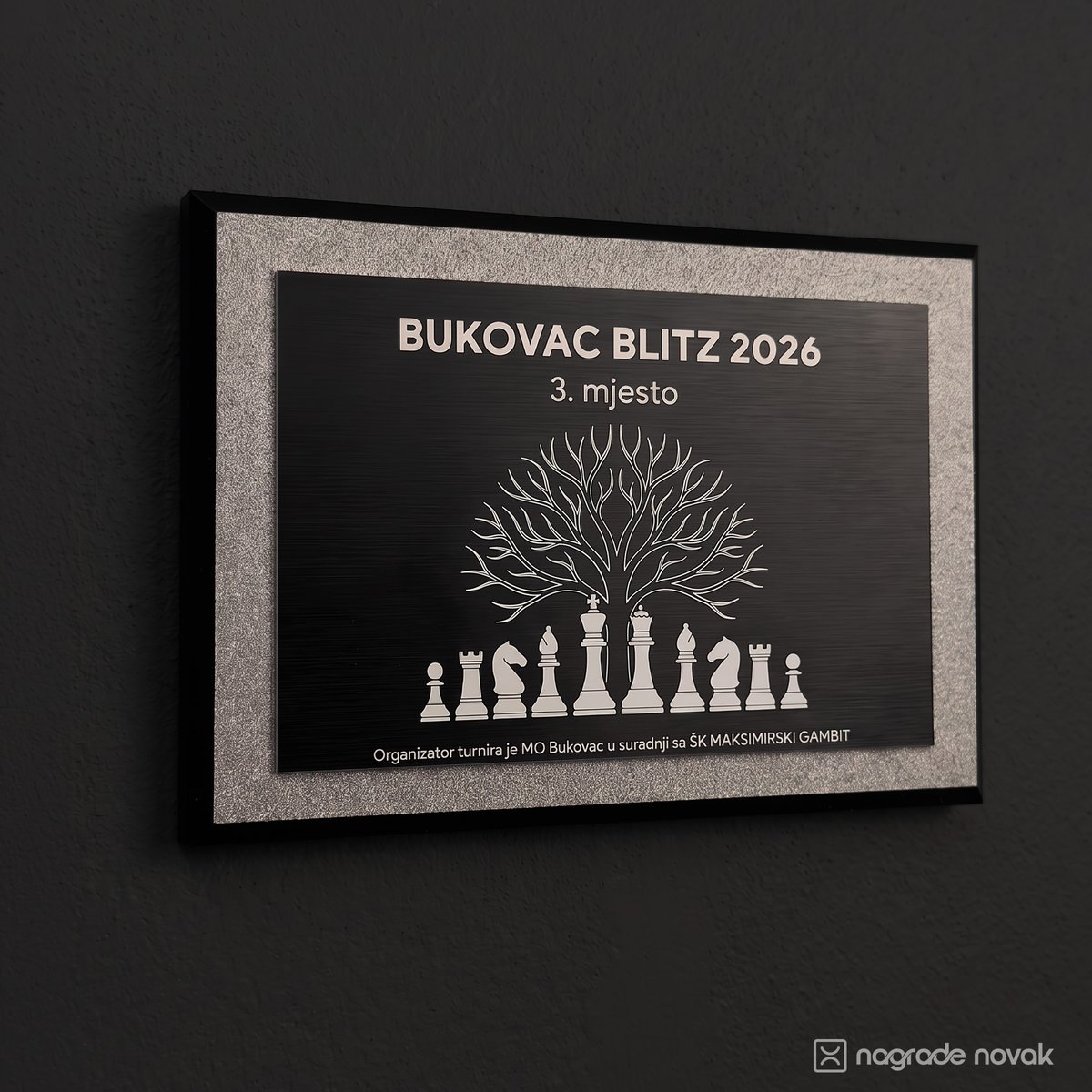 3rd place plaque "BUKOVAC BLITZ 2026, 3. mjesto" with a tree above chess pieces, mounted on a dark wall