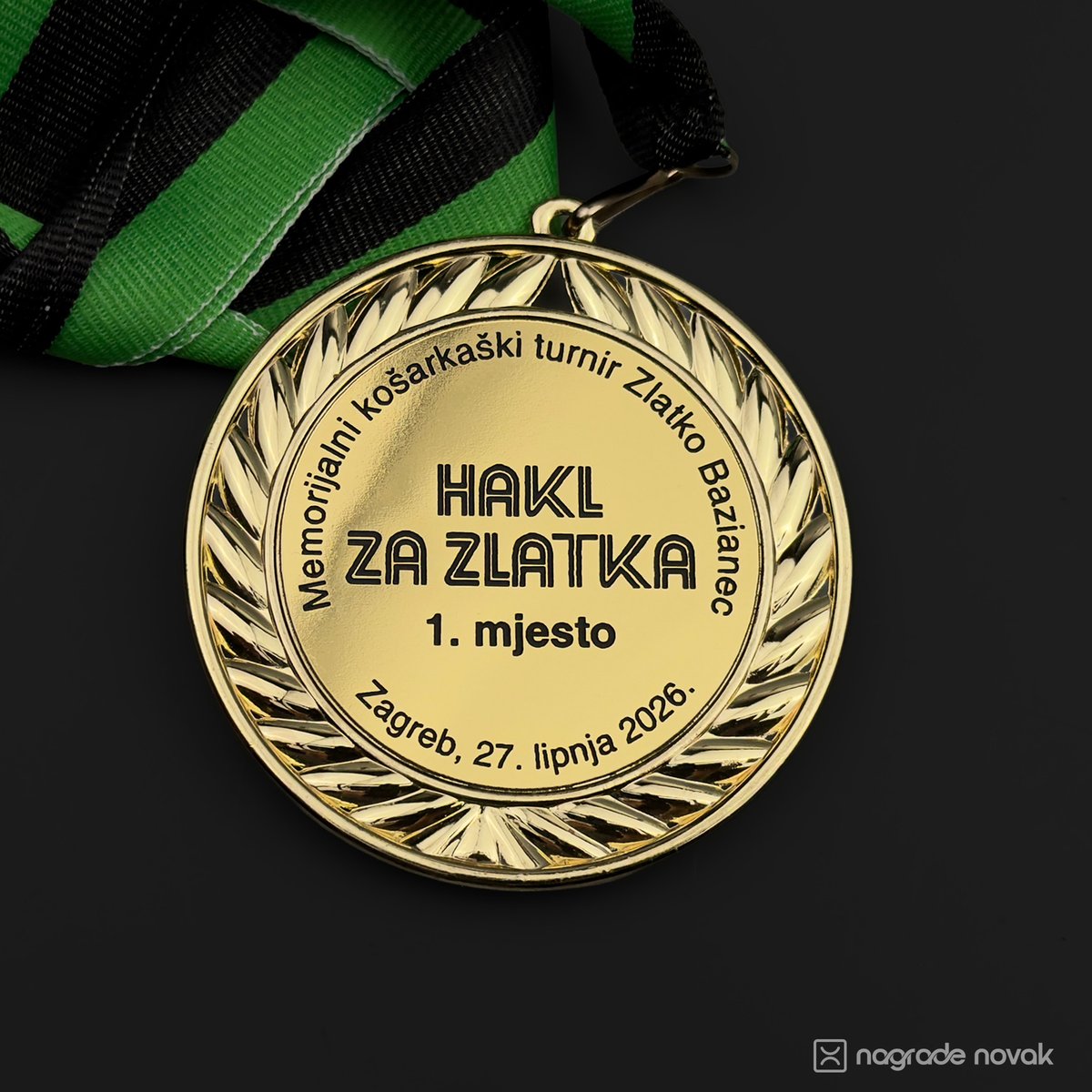 Close-up of the gold 1st place medal with laurel wreath and engraved "HAKL ZA ZLATKA" text, with a green and black ribbon