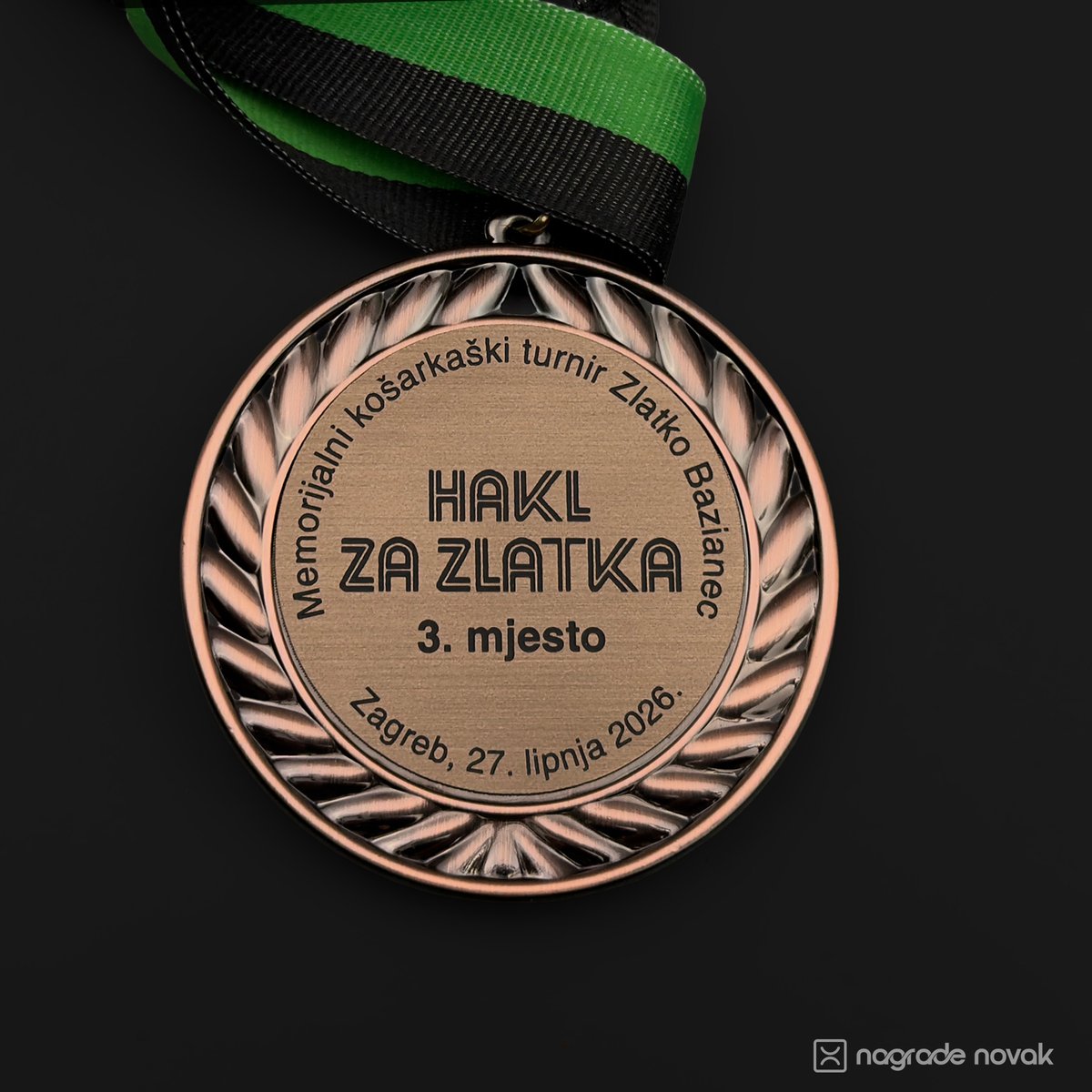 Close-up of the bronze 3rd place medal with laurel wreath and engraved "HAKL ZA ZLATKA" text, with a green and black ribbon